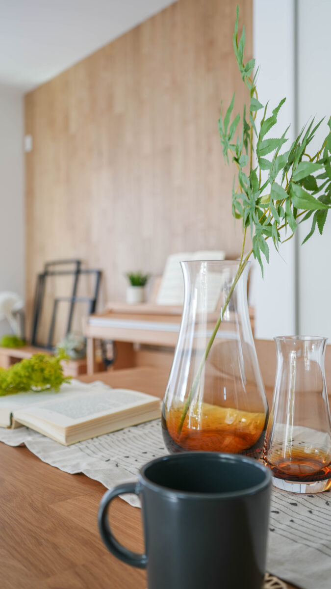 坪庭のシンボルツリーと調和するモミジが生けられたダイニングテーブル。中央のみにシンプルに設えがされているのが特徴。