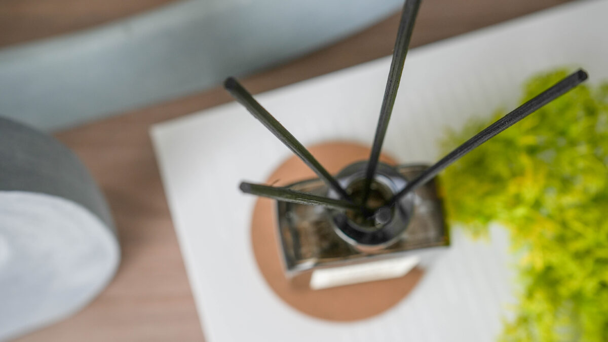 ルームフレグランスを上から捉えたカット。ガラスボトルから伸びるスティックが放射状に広がり、シンプルでモダンな印象を与えている。