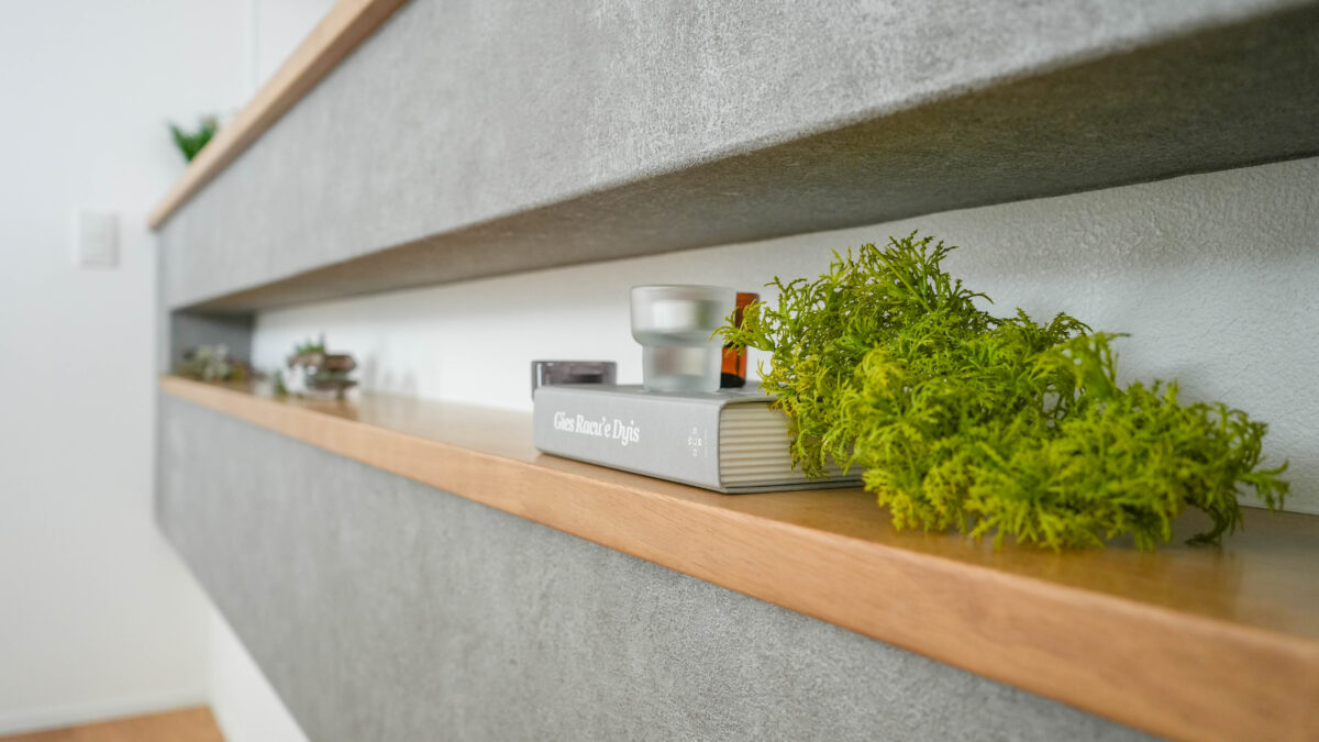 キッチンの腰壁に設けられた横長のニッチに同色の本とさりげなく添えられたグリーンがアクセントとなっている。